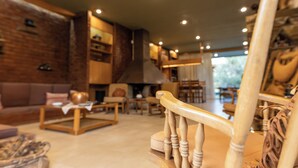 A cozy living room with a fireplace, wooden furniture, and a view of the outdoors. - Retro house (Rafina)