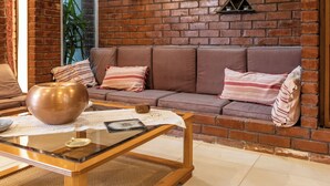A living room with a brick wall, a sofa, a coffee table, and a decorative bowl. - Retro house (Rafina)