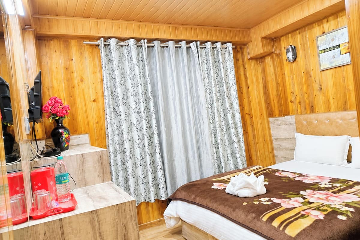 A wooden-paneled room with a bed, a small table with a vase of flowers, and a shower curtain.