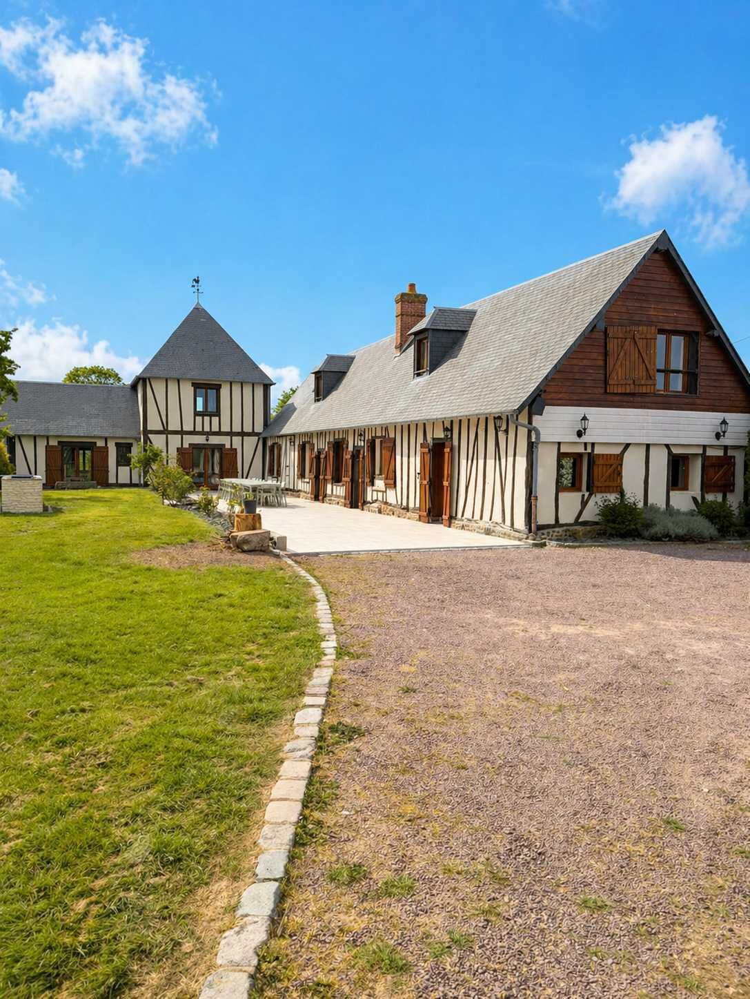 A traditional half-timbered house with a gravel driveway and a well-maintained lawn.