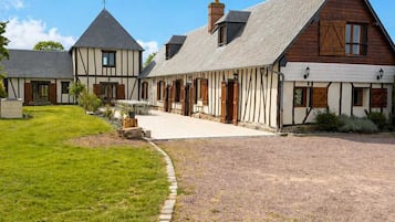 A traditional half-timbered house with a gravel driveway and a well-maintained lawn.