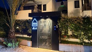 A modern hotel entrance with a gated entrance, a sign indicating 'AQUA SUITES,' and a security keypad.