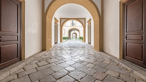 A corridor with stone flooring, wooden doors, and arches. - Palazzo Sambuca Charming by Wonderful Italy (Palermo)