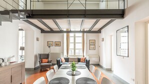 A spacious dining area with a high ceiling, a central plant, and a view of the city through large windows. - Palazzo Sambuca Charming by Wonderful Italy (Palermo)
