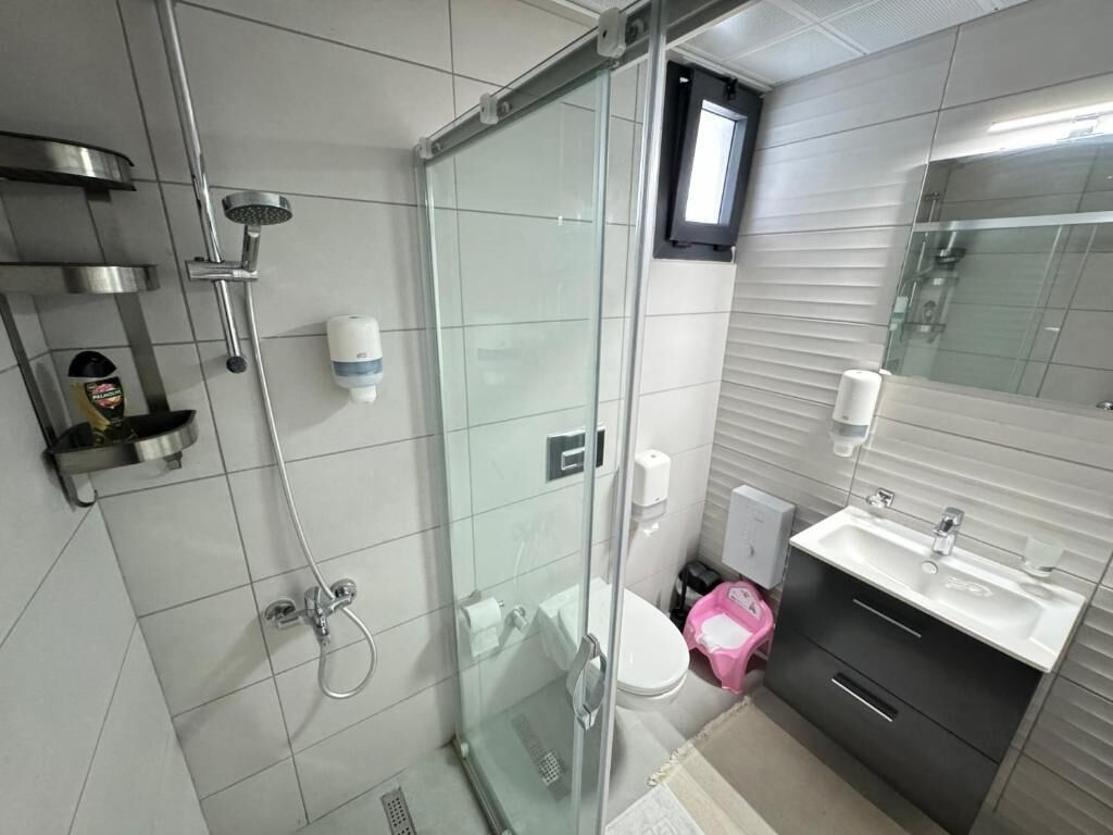 Un baño moderno con cabina de ducha de vidrio, inodoro, lavabo y espejo.