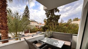A balcony with wicker furniture, a glass table, and a view of the surrounding area. - ORANGE SUİTE 2+1 Family Apartment - 200m Walking Distance to the Beach (Kemer)