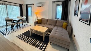 A modern living room with a sofa, coffee table, and dining area. - ORANGE SUİTE 2+1 Family Apartment - 200m Walking Distance to the Beach (Kemer)