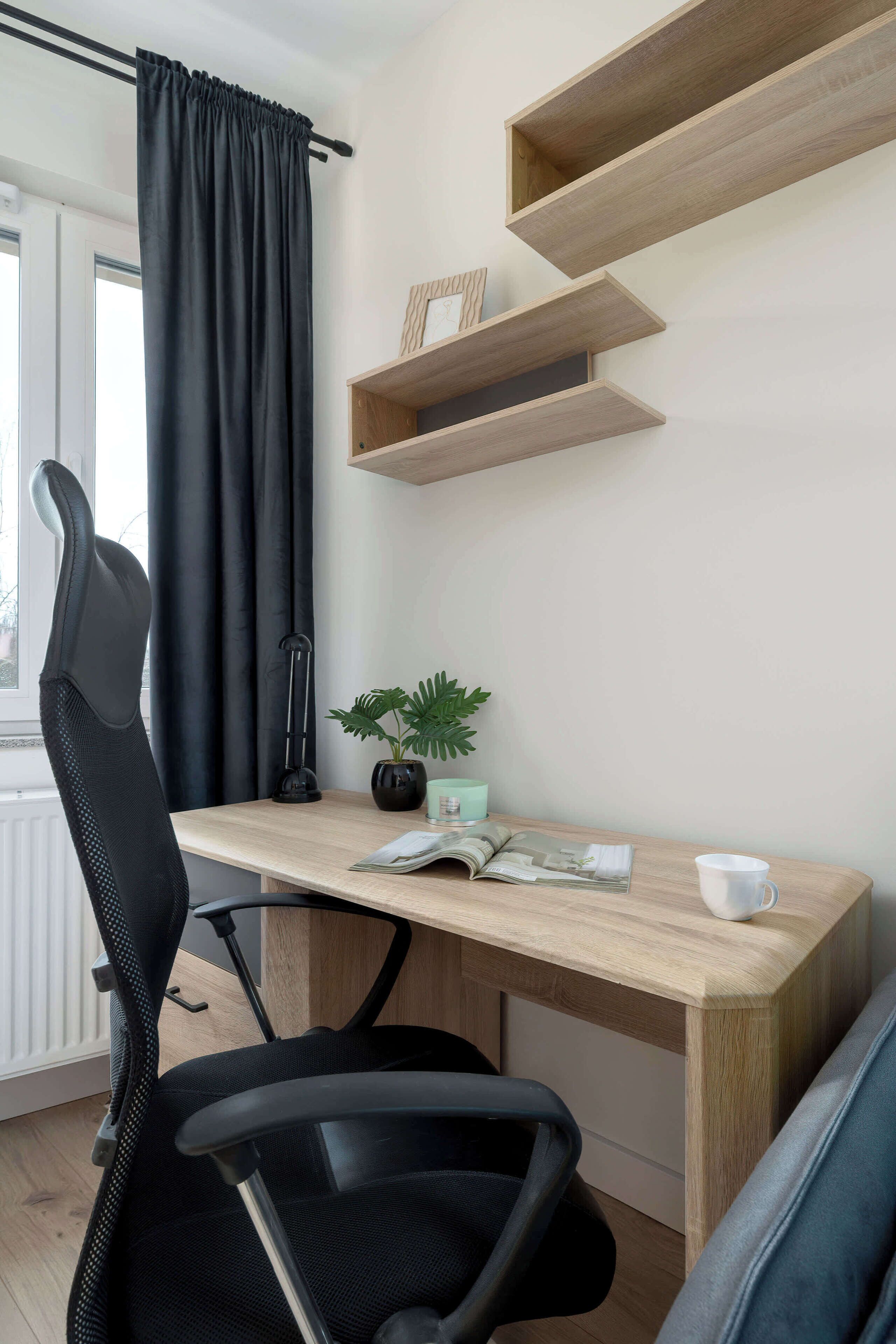 Een moderne bureaustoel, een bureau met een plant en houten planken.