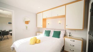 Ein modernes Hotelzimmer mit einem großen Bett, einem Nachttisch, einem Kleiderschrank und einem Spiegel an der Wand.