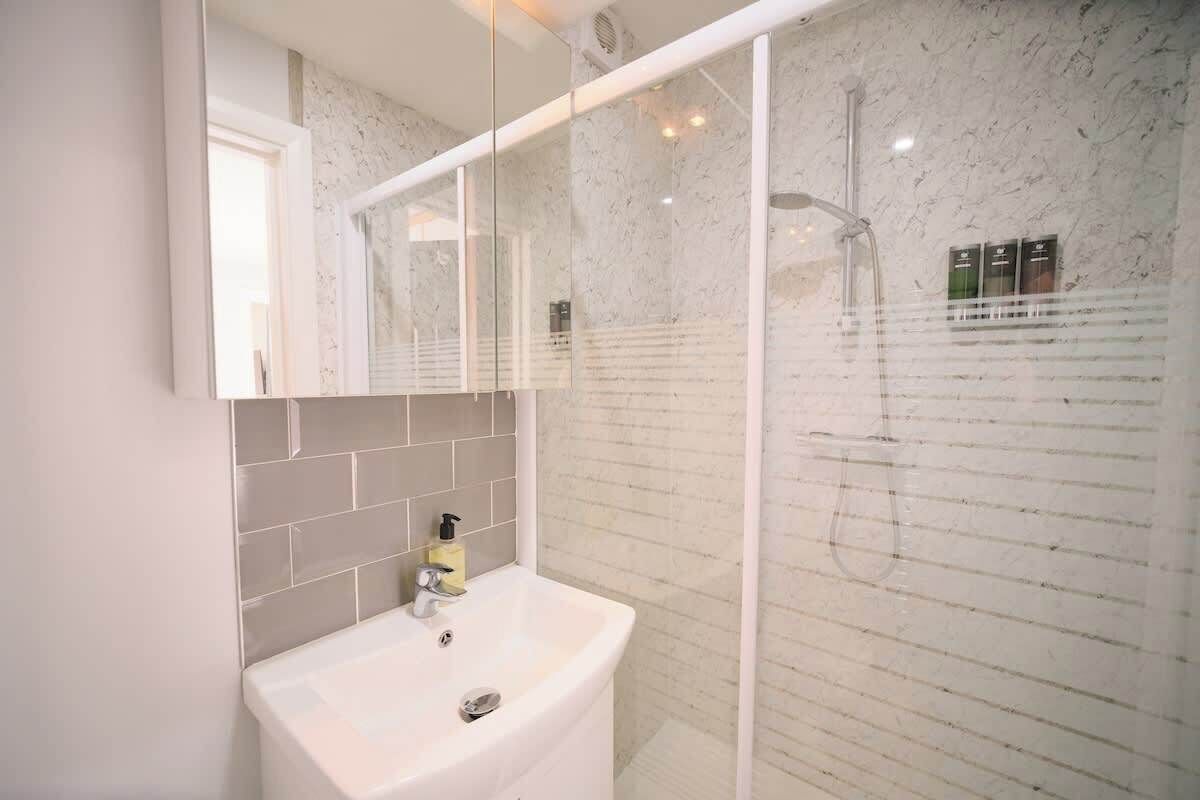 A bathroom with a white sink, a mirror, and a glass-enclosed shower area.