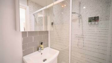 A bathroom with a white sink, a mirror, and a glass-enclosed shower area.