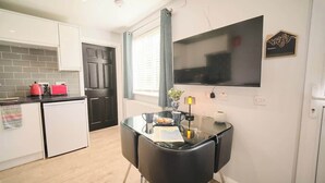 Eine moderne Küche mit Essbereich, einem Flachbildfernseher und einem kleinen Kühlschrank.