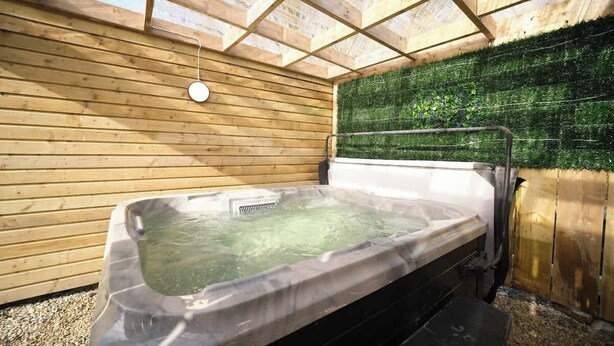 Ein Whirlpool in einem Holzraum mit grüner Wand und Holzboden.