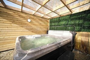 A hot tub in a wooden room with a green wall and a wooden ceiling.