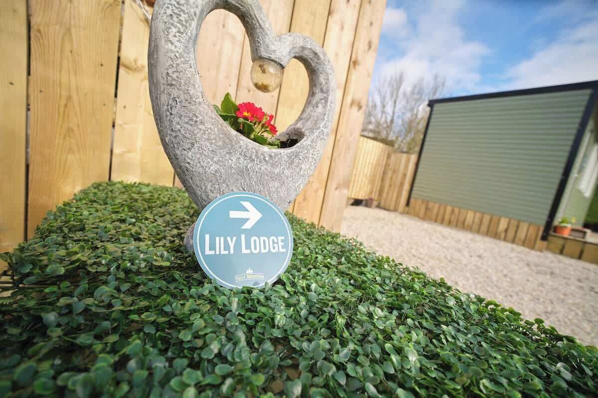 Un pot de fleurs en forme de cœur, agrémenté d’une plaque indiquant « Lily Lodge » et d’une flèche directionnelle.