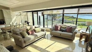 A spacious living room with two sofas, a coffee table, and a view of the outdoors. - Atlantic View Retreat (Sleeps 6,Pet Friendly,Wifi) (Downings)