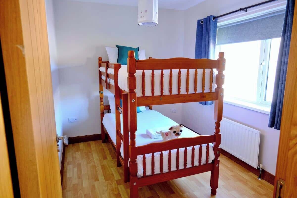 Ein Zimmer mit einem Etagenbett, einem Vorhangfenster, einem Heizkörper und einer Tür.