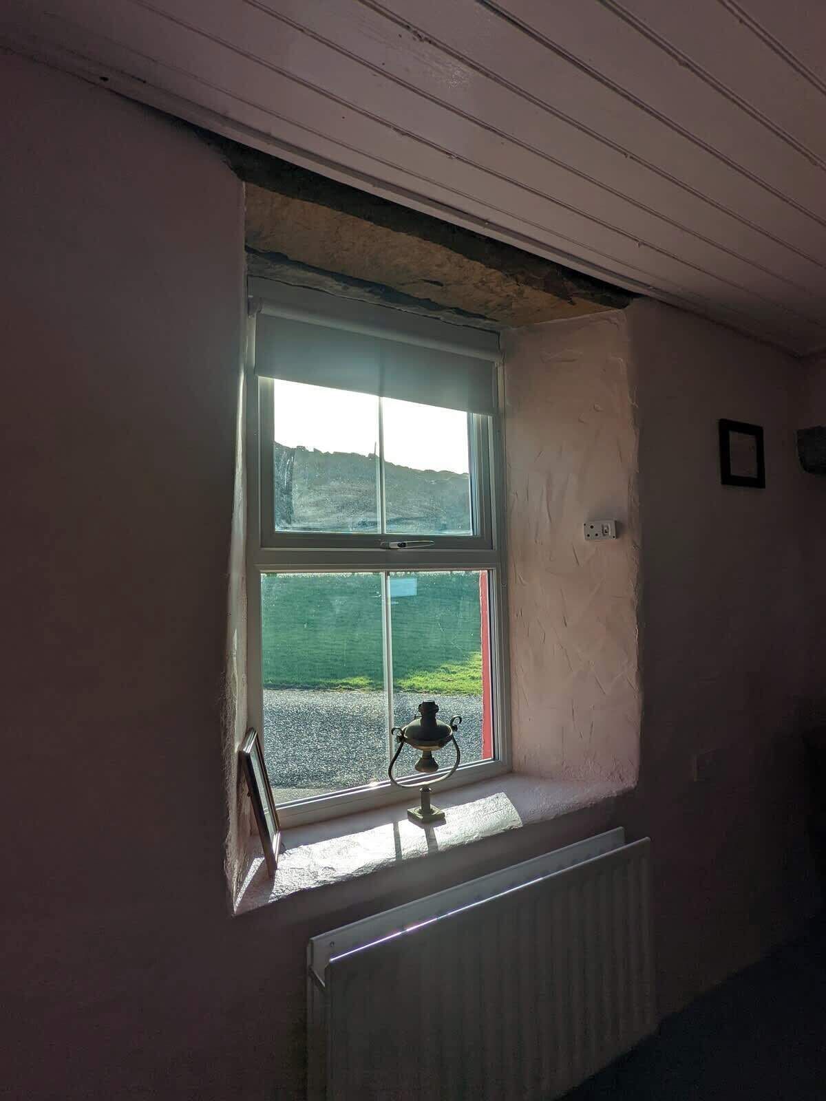 A room with a window, a radiator, and a small table with a lamp.