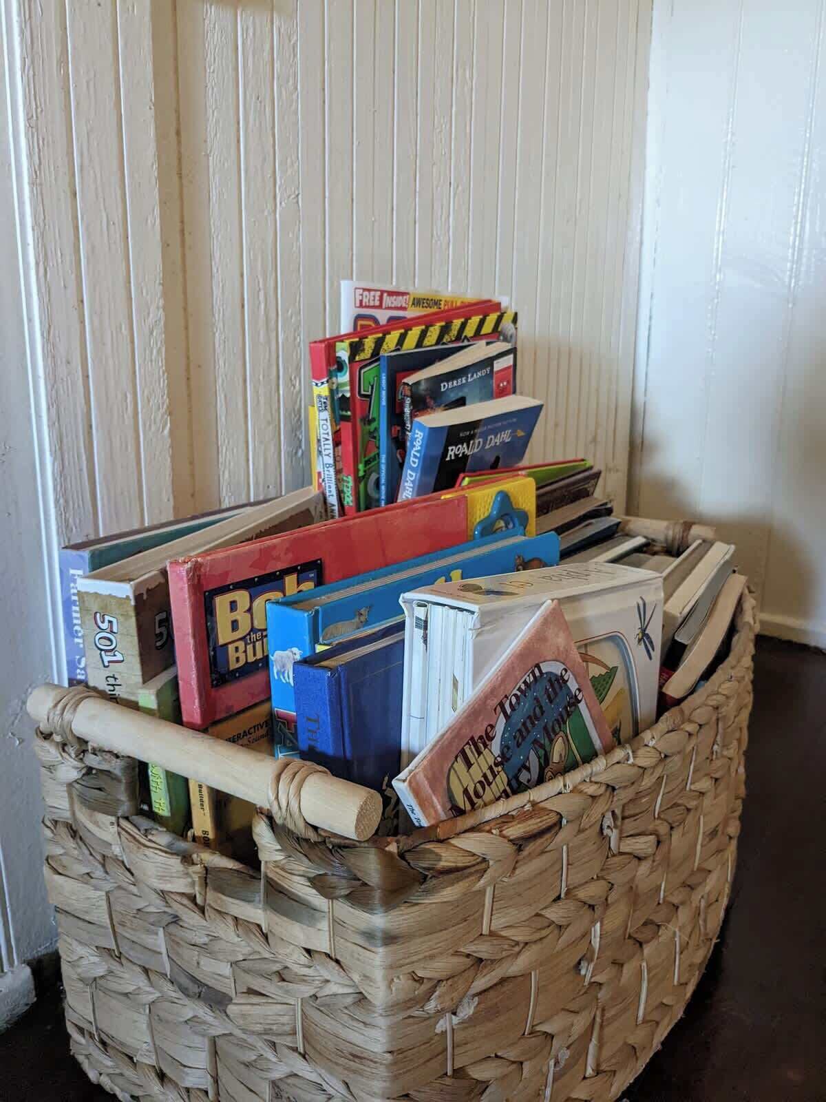 Ein Korbbasket gefüllt mit verschiedenen Büchern und einem zusammengerollten Gegenstand.