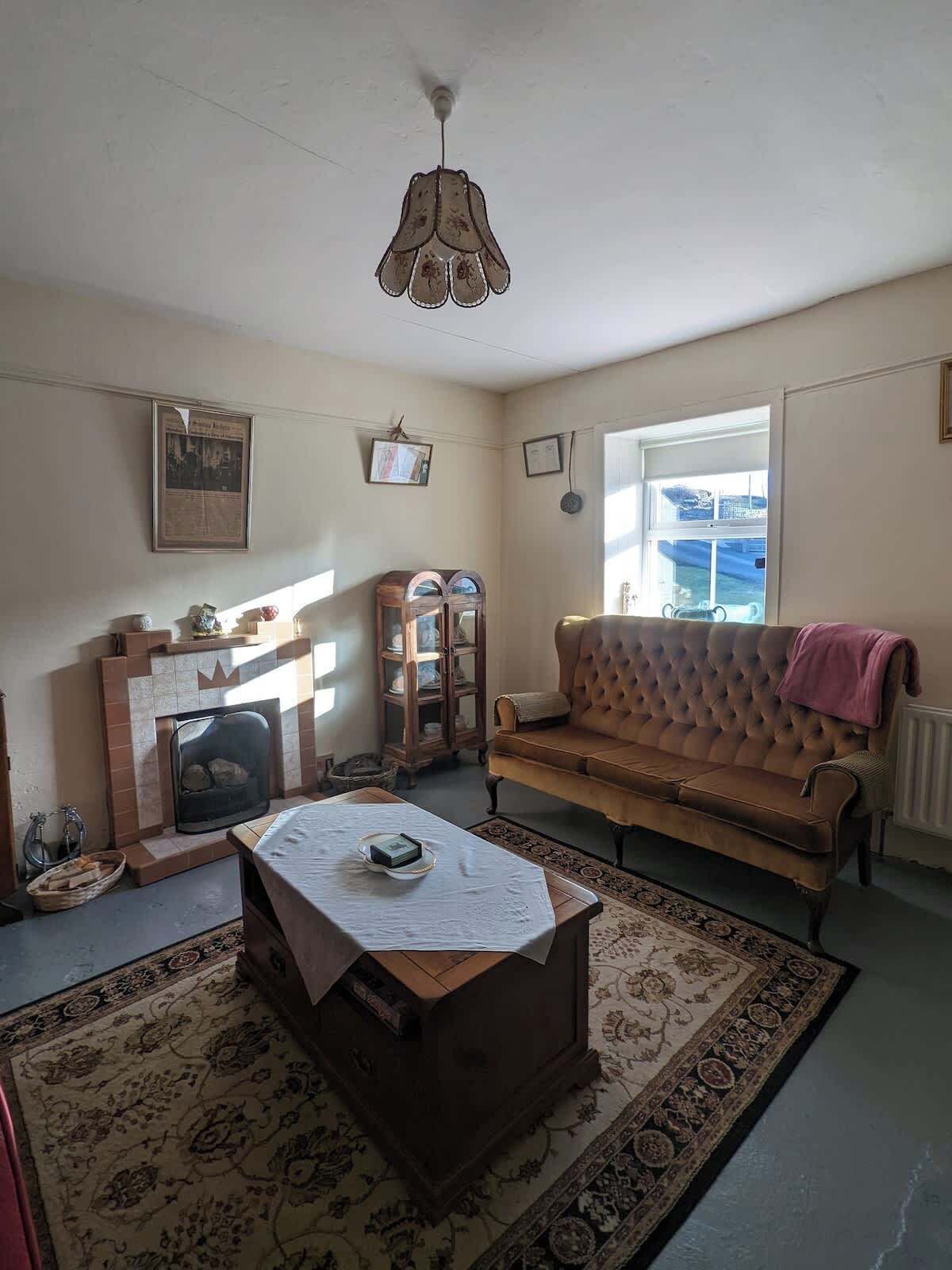 A living room with a fireplace, a sofa, a table, and a hanging light fixture.