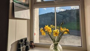 Een raam met uitzicht op een landschap, een vaas met bloemen en een agenda.