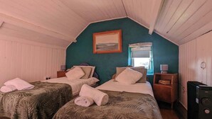 Een kamer met twee bedden, een schilderij aan de muur, een raam en een verwarming.