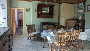 Een eethoek met een houten tafel, stoelen, een kast en uitzicht op een andere kamer.
