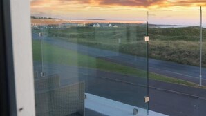 Une vue par la fenêtre donnant sur une route, avec le soleil couchant à l'horizon.