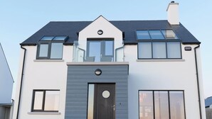 Une maison à deux étages avec un toit sombre, une porte d’entrée et un petit balcon.