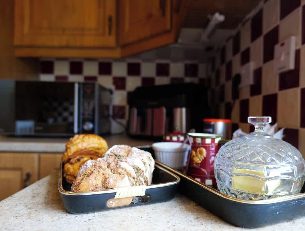 A kitchen counter with a tray of pastries, a glass container, and a microwave in the background.