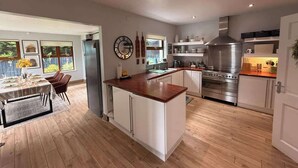 A modern kitchen with white cabinets, a wooden countertop, and stainless steel appliances. - Modern 4 Bed,3 Bath Detached Home with Sea View (Quigley's Point)