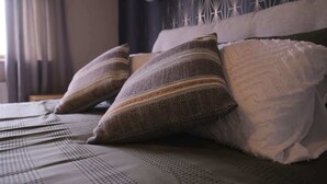A bed with patterned bedding and pillows, a geometric wall design, and a hanging light fixture. - Modern 4 Bed,3 Bath Detached Home with Sea View (Quigley's Point)