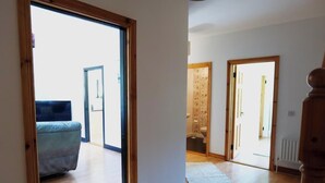 A hallway with a blue sofa, wooden doors, and a radiator. - 4BR Workers Accommodation | Sleeps 7 | Wi-Fi (Letterkenny)