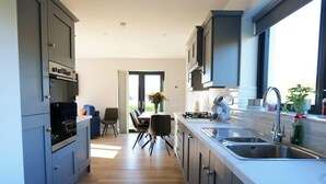 Uma cozinha moderna com eletrodomésticos embutidos, uma área de refeições com cadeiras e uma grande janela que oferece luz natural.