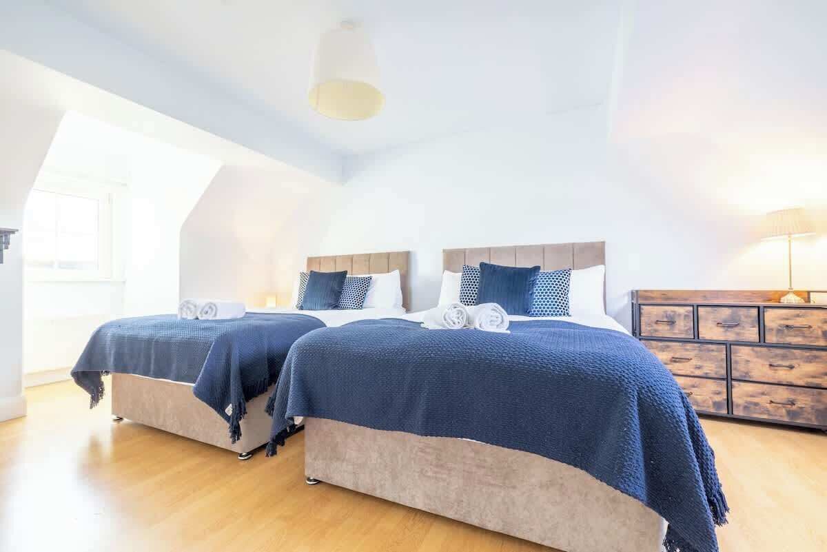 A bedroom with two beds, wooden headboards, and a wooden dresser.