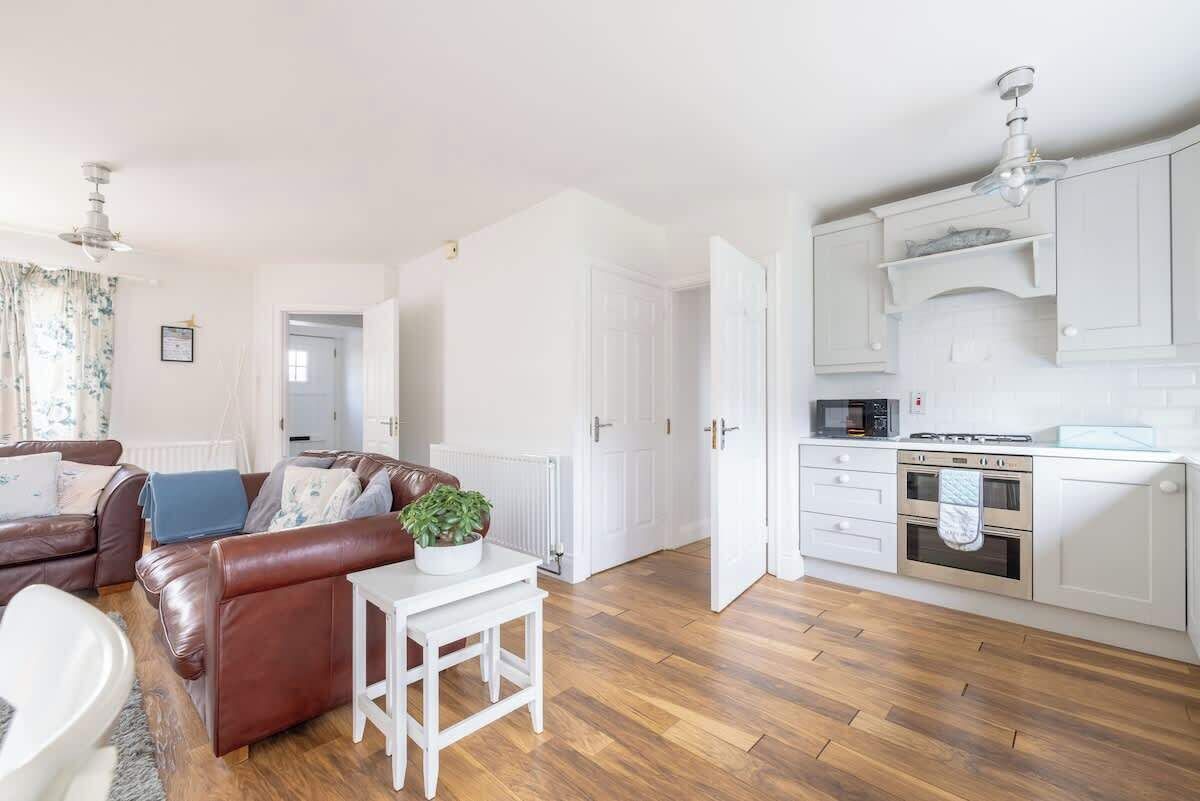 Een moderne keuken met witte kastjes, een magnetron en een oven.