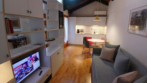 Un intérieur moderne comprenant un téléviseur, un canapé, une table à manger et un coin cuisine.
