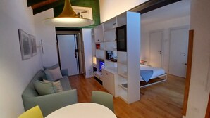 Un espace de vie compact comprenant un canapé, une table à manger, un téléviseur et un lit.