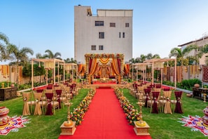 An outdoor event space with a red carpet, floral decorations, and a stage. - Lords Inn Sangam (Bhopal)