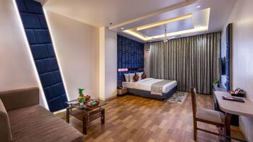 A modern hotel room with a bed, a desk, a chair, and a sofa.