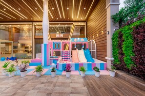 Un espace de jeux intérieur avec des toboggans et des structures d’escalade.