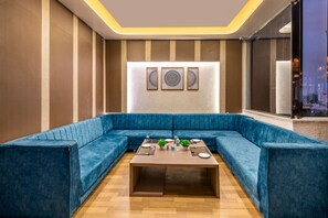 Un espace salon moderne avec un canapé d’angle bleu recouvert de tissu, une table basse en bois et deux œuvres d’art encadrées accrochées au mur.
