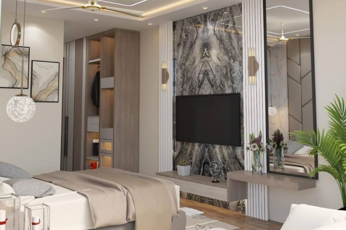 A modern bedroom with a large flat-screen TV, a marble accent wall, a walk-in closet, and a bedside table with a vase.