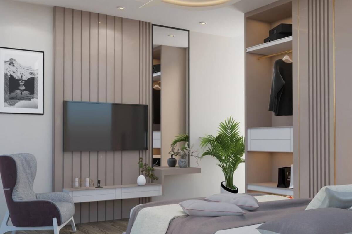 A modern bedroom with a bed, a chair, a TV, a wardrobe, and a plant.