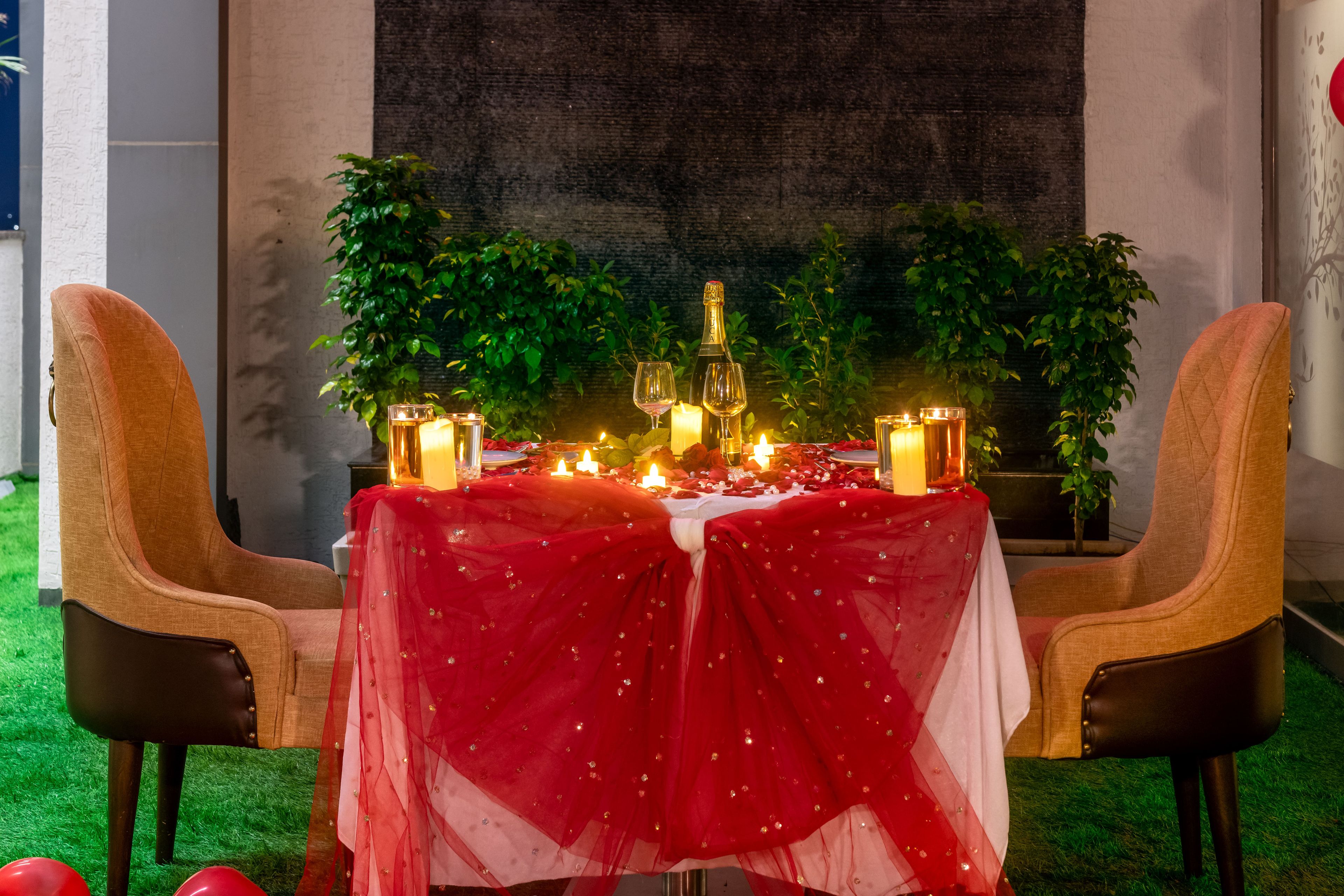 Een romantische diner setting met een tafel voor twee, kaarsen en een fles champagne.