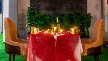 Een romantische diner setting met een tafel voor twee, kaarsen en een fles champagne.