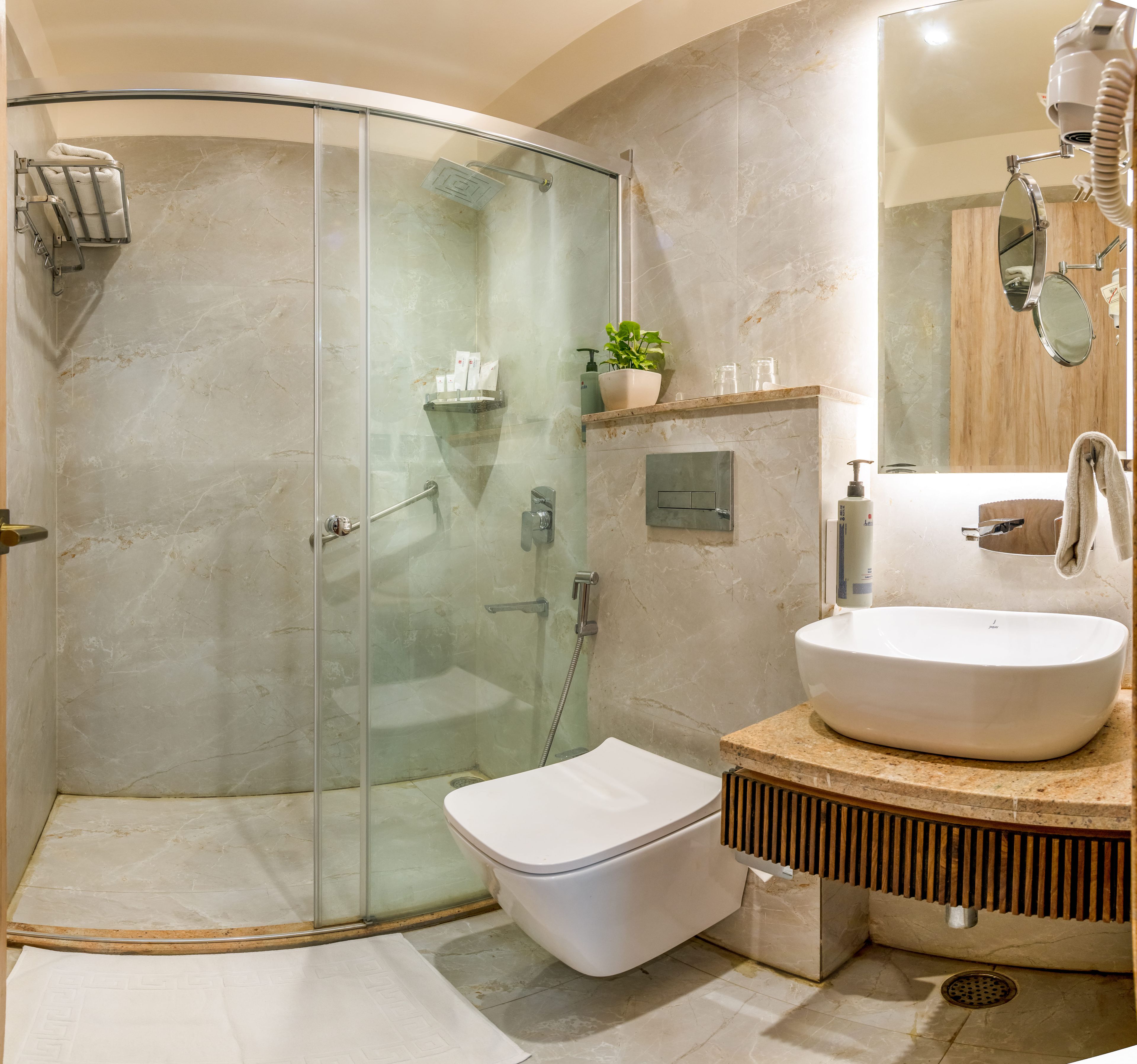 A modern bathroom with a glass-enclosed shower, a white toilet, and a sink with a wooden vanity.