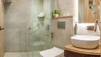 A modern bathroom with a glass-enclosed shower, a white toilet, and a sink with a wooden vanity.