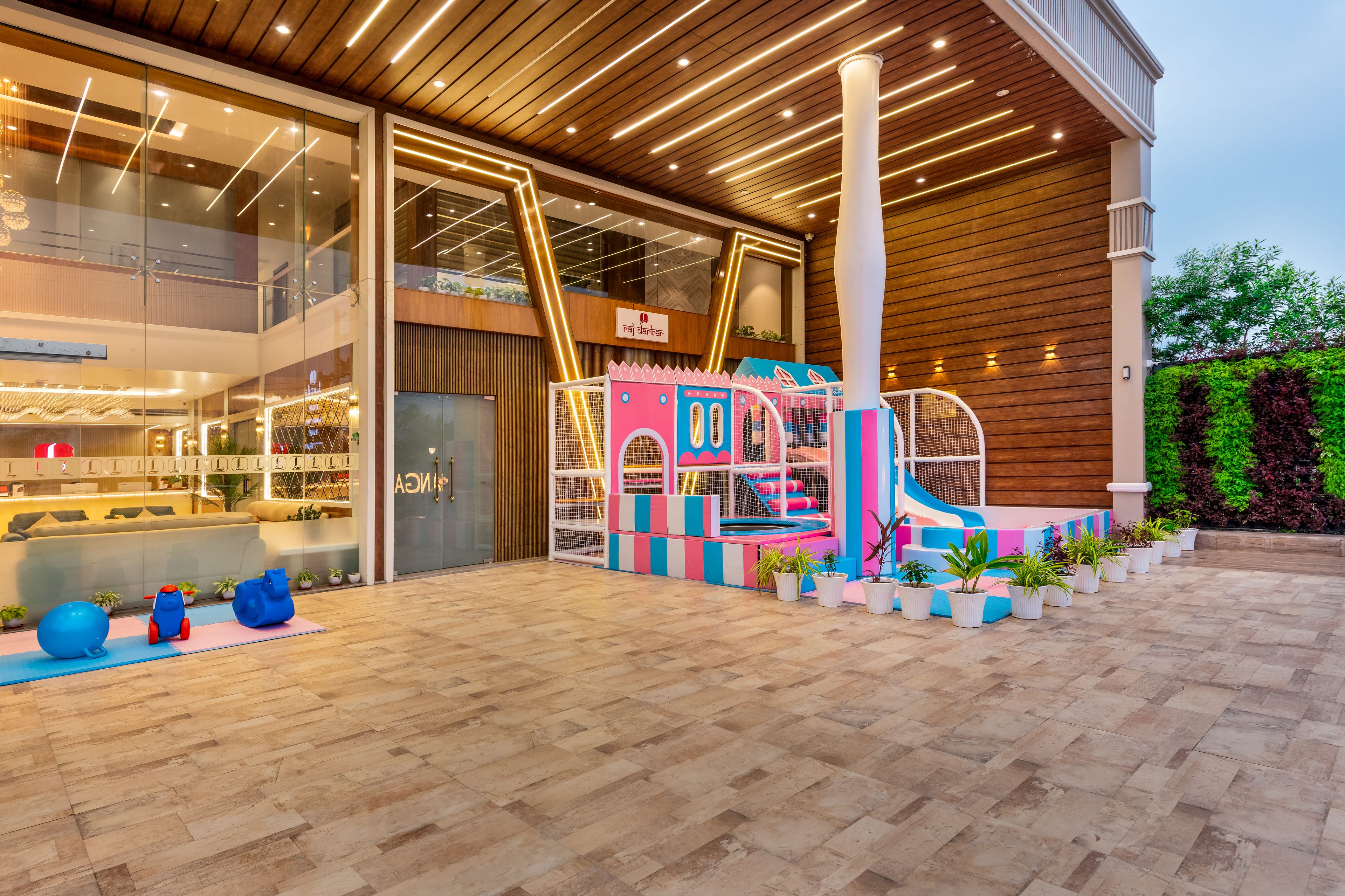 A modern hotel lobby with a play area, a reception desk, and a large glass wall.