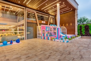 A modern hotel lobby with a play area, a reception desk, and a large glass wall. - Lords Inn Sangam (Bhopal)